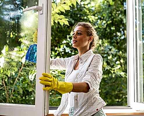 Frau putzt Fenster